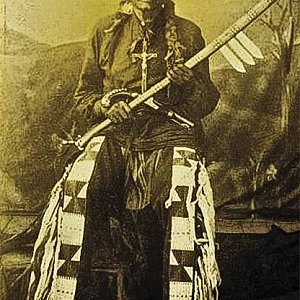 На этой фотографии 1870-х годов, сделанной в Форт Йейтсе, территория Дакота, изображен вождь Арикара Одинокий пес, позирующий со своей боевой дубинкой, украшенной тяжелыми накладками, лезвиями ножа для снятия шкур и украшенным накладками конным пистолетом