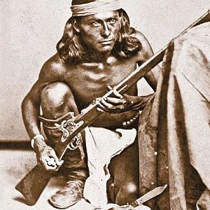 Разведчик из племени апачей в раннем Тусоне, территория Аризона, держит выданный правительством конверсионный мушкет Аллина 2-й модели калибра .50-70 рядом с револьвером Smith & Wesson .44 American и ножом для снятия шкур.